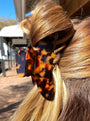 Close-up of a hair bun with a tortoiseshell clip against a blurred indoor background