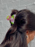 Person with a ponytail and colorful hair tie against a gray brick wall
