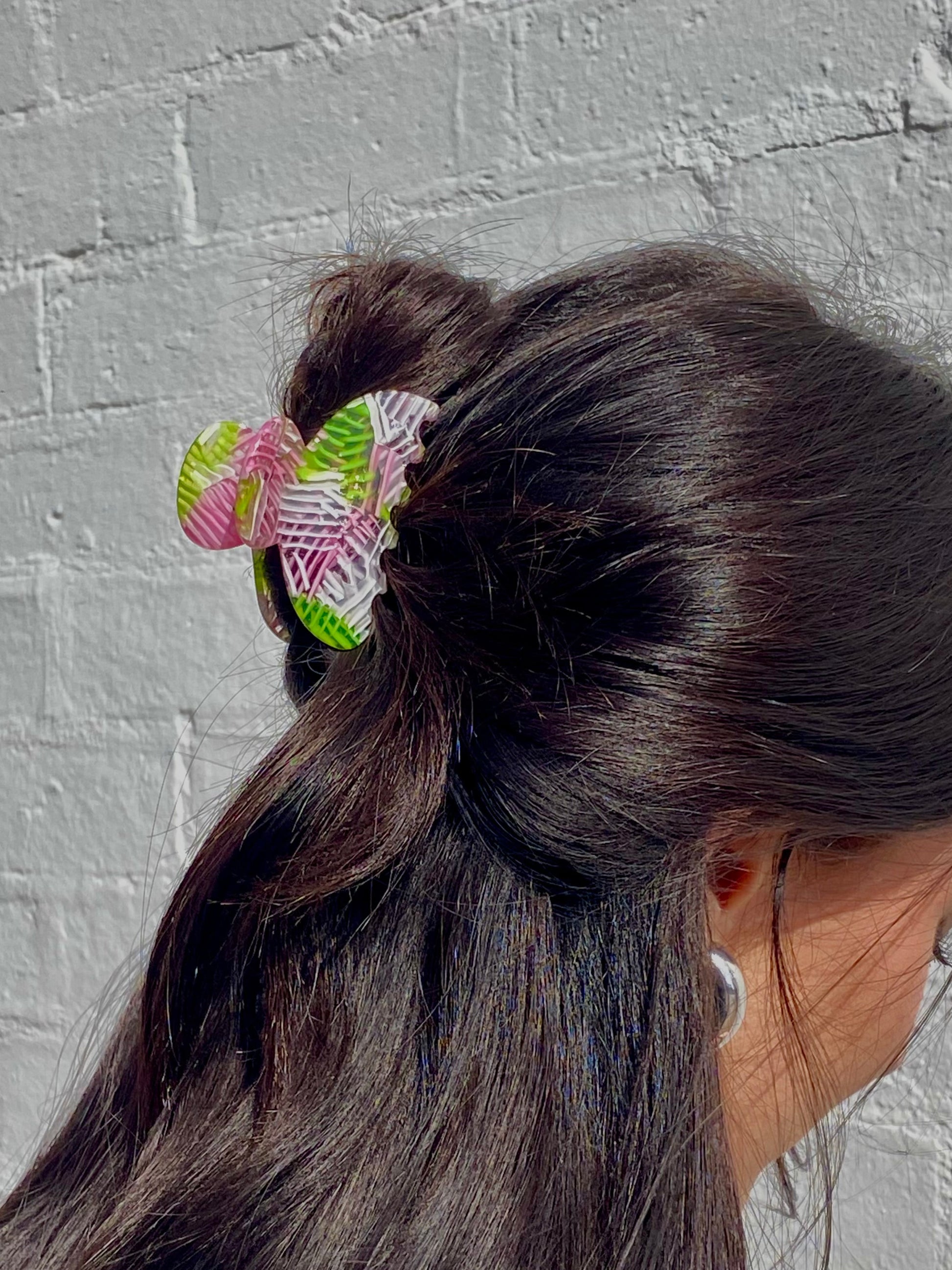 Person with a ponytail and colorful hair tie against a gray brick wall