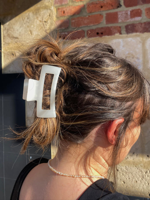 Person with a hair clip in their bun against a brick wall.