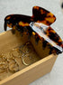 Tortoiseshell hair comb with 'Goldn' branding in a wooden box with gold rings.