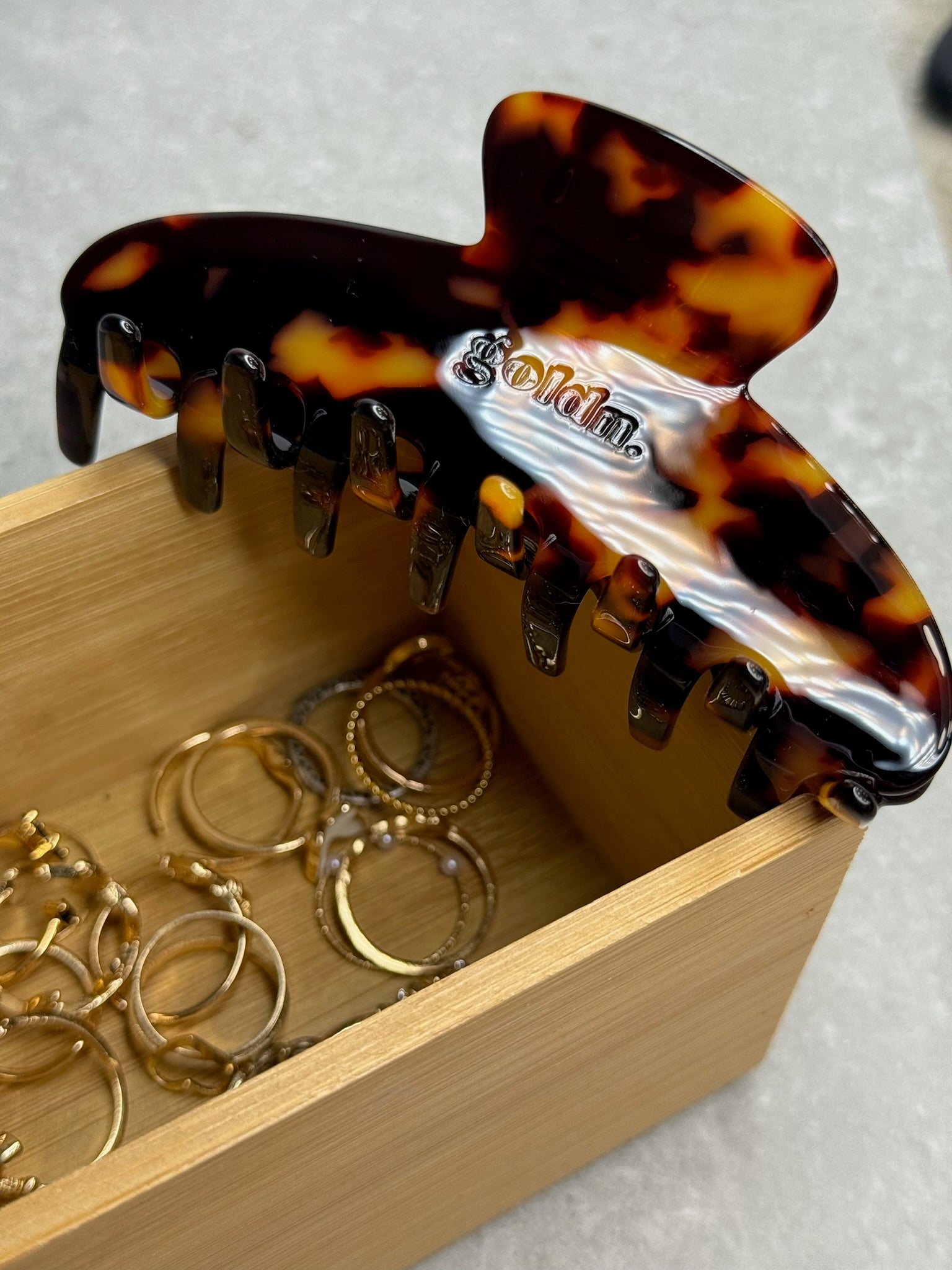 Tortoiseshell hair comb with 'Goldn' branding in a wooden box with gold rings.