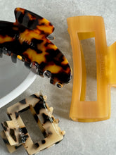 Load image into Gallery viewer, Two hair clips, one tortoiseshell and one amber, on a light gray background.
