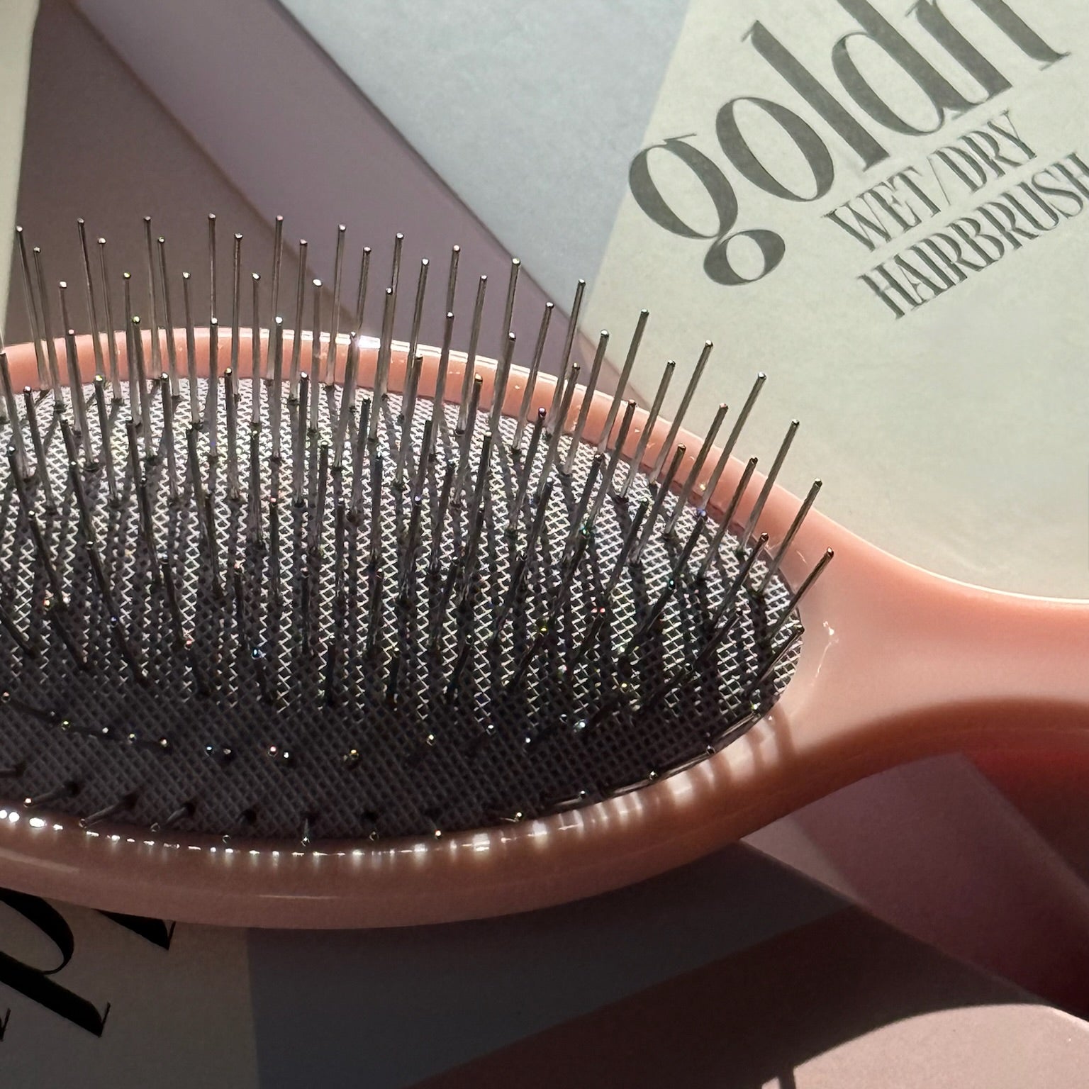 Pink hairbrush with black bristles on a geometric-patterned background