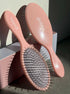 Pink hairbrushes with 'Gold'n' logo on a neutral background golden hour