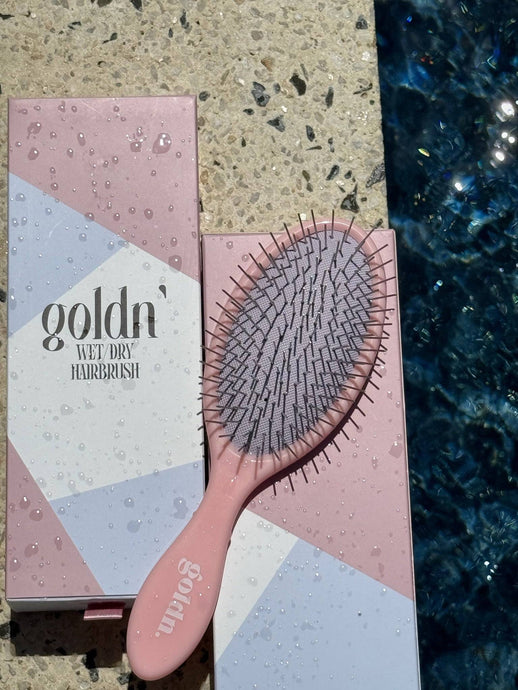 Goldn' Wet/Dry HairBrush with durable metal bristles, designed for seamless detangling on wet and dry hair. Stylish pink handle with sleek packaging.