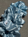 Blue satin scrunchies on a gray surface
