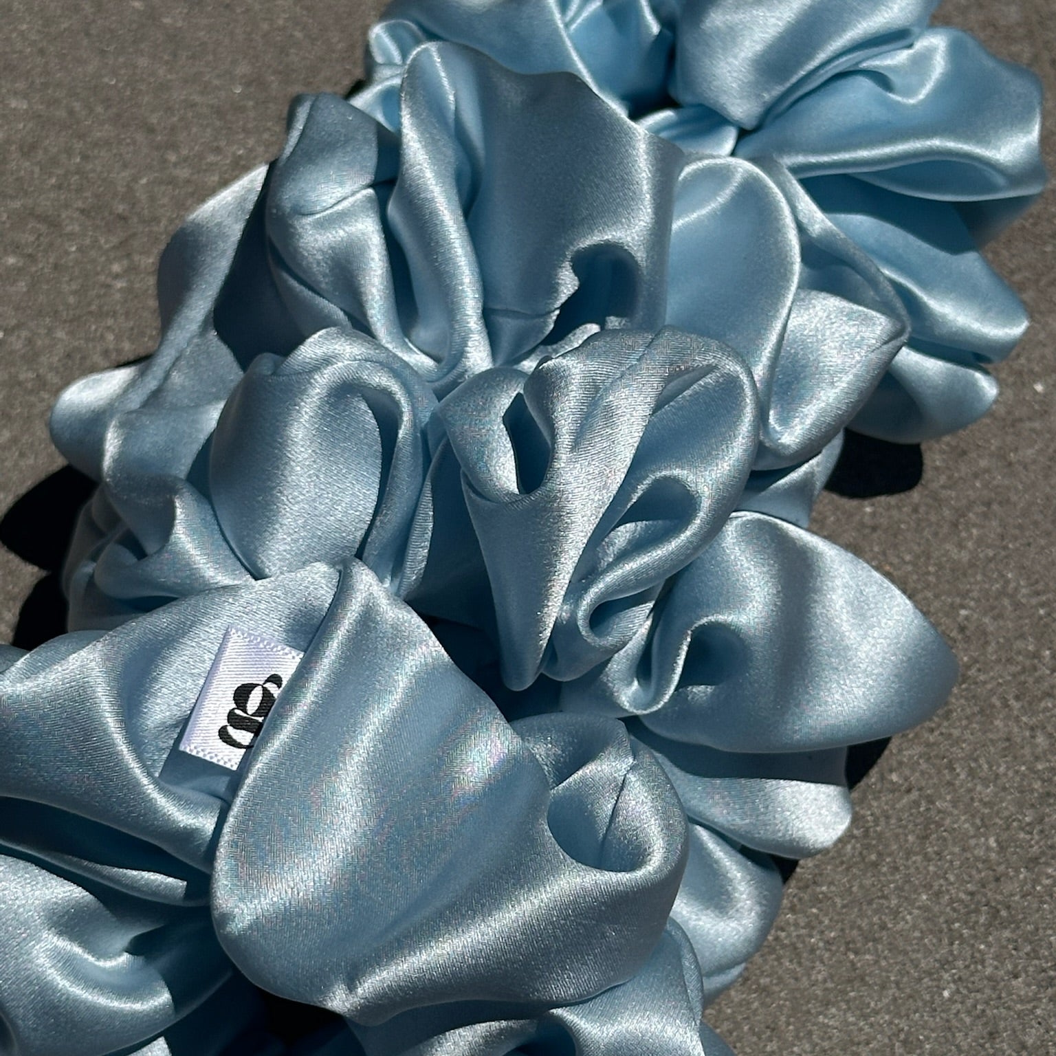 Blue satin scrunchies on a gray surface