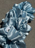Blue satin scrunchies on a gray surface