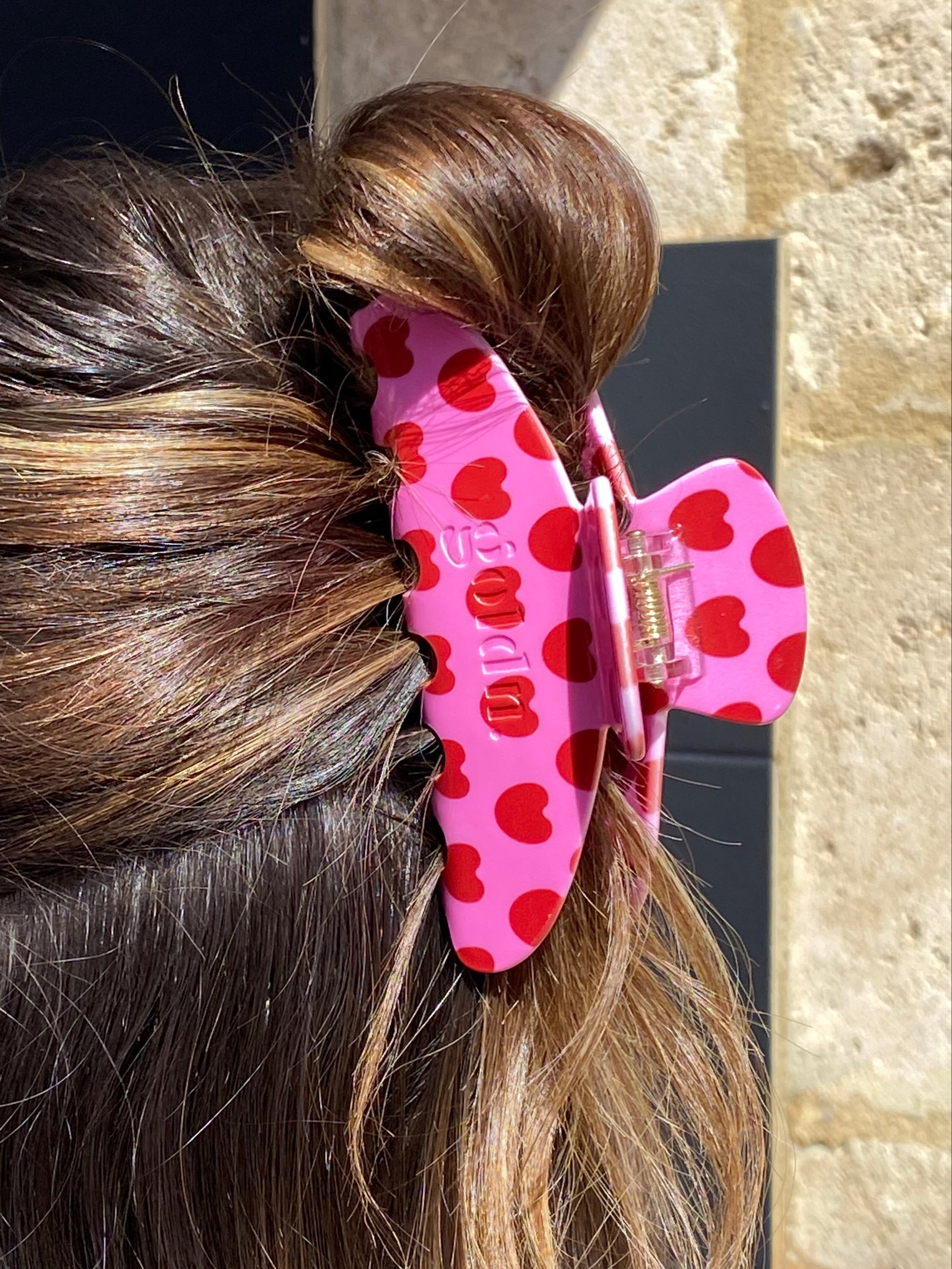 Close-up of a hair clip with heart pattern on a person's hair against a blurred background