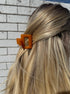 Close-up of blonde hair with a brown clip on a tiled floor background