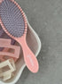 Pink hairbrush with bristle head and wooden clips on a gray surface